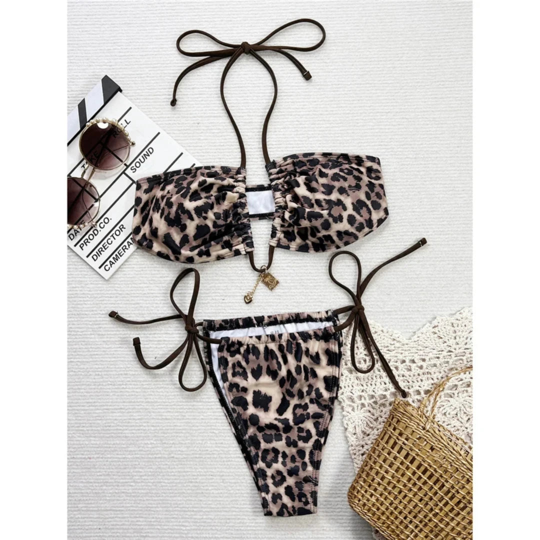 Bikini imprimé léopard à bretelles marron posé à plat sur fond clair, décolleté échancré avec breloque dorée au centre