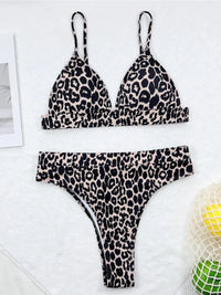 Bikini triangle et taille haute imprimé léopard noir et crème posé à plat sur fond blanc, filet et citron à côté