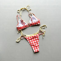 Bikini triangle à carreaux rouge et blanc avec lacets beiges, posé à plat sur fond gris