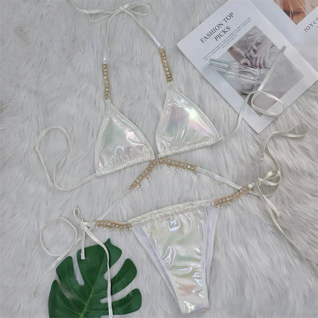 Bikini aspect simili cuir blanc irisé posé à plat sur une fourrure blanche, avec feuille verte et chaîne