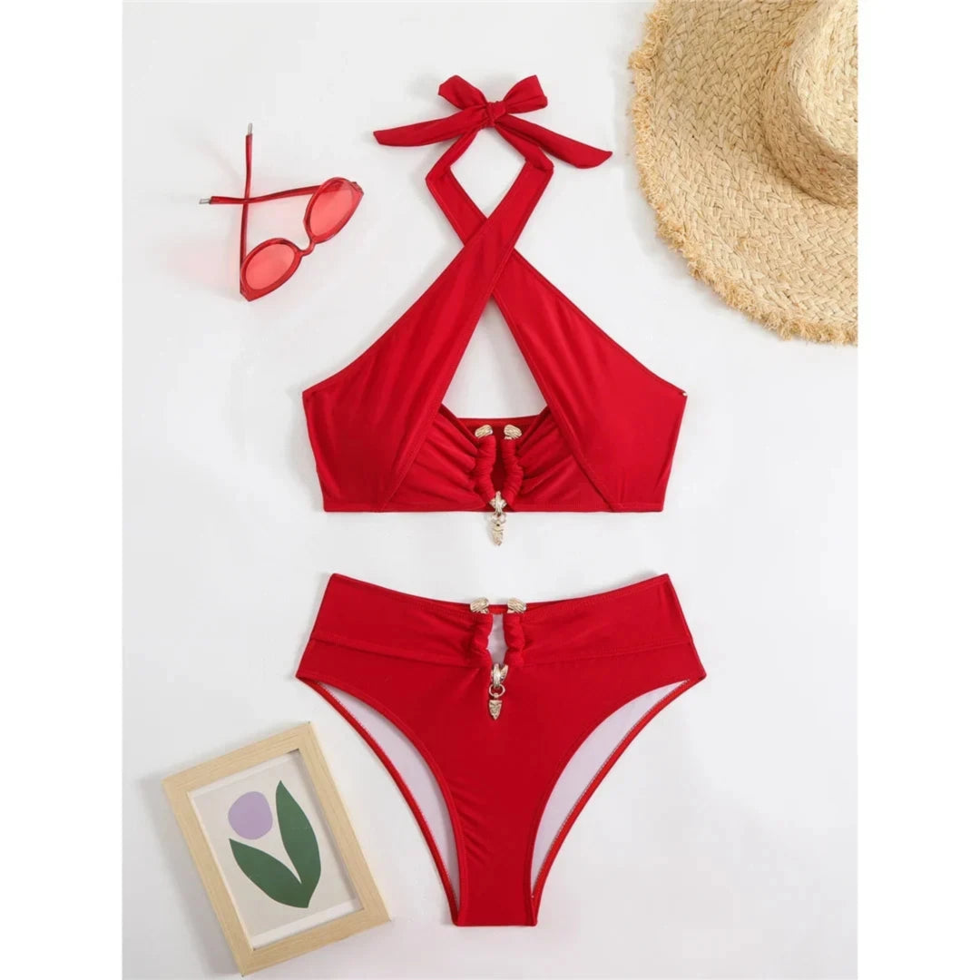 Bikini taille haute tour de cou à découpes rouge posé à plat sur fond blanc, lunettes et chapeau de paille à côté