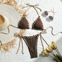 Bikini tour de cou marron foncé posé à plat sur une natte ronde, coquillages et étoiles de mer à côté