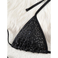 Gros plan sur le haut triangle noir à paillettes du bikini, bordure fine et bretelles halter