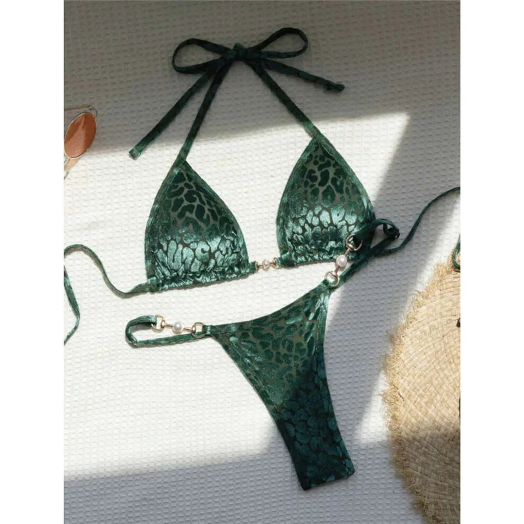 Bikini string vert imprimé léopard posé à plat sur un tissu blanc, haut triangle à lien et bas à anneaux métalliques