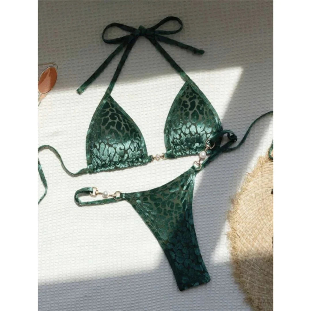 Bikini string triangle sans armatures imprimé léopard vert posé à plat sur fond blanc, bretelles fines et chapeau de paille