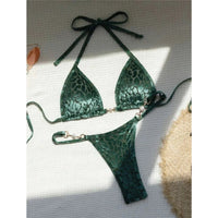 Bikini string triangle sans armatures imprimé léopard vert posé à plat sur fond blanc, bretelles fines et chapeau de paille
