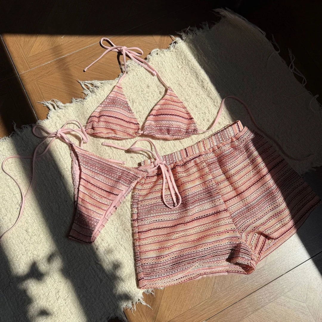 Ensemble rayé rose pêche posé à plat sur un tapis en tissu, haut à lanières, short taille élastique et bas ficelé