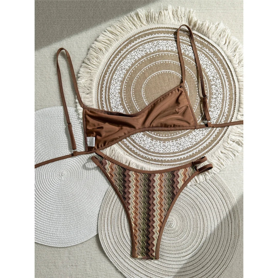 Bikini brésilien marron et vert posé à plat, haut uni marron et bas à chevrons sur un tapis rond en paille