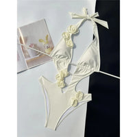 Maillot de bain une pièce décolleté V fleurs 3D blanc cassé posé à plat, fleurs crème sur les bonnets et découpes latérales