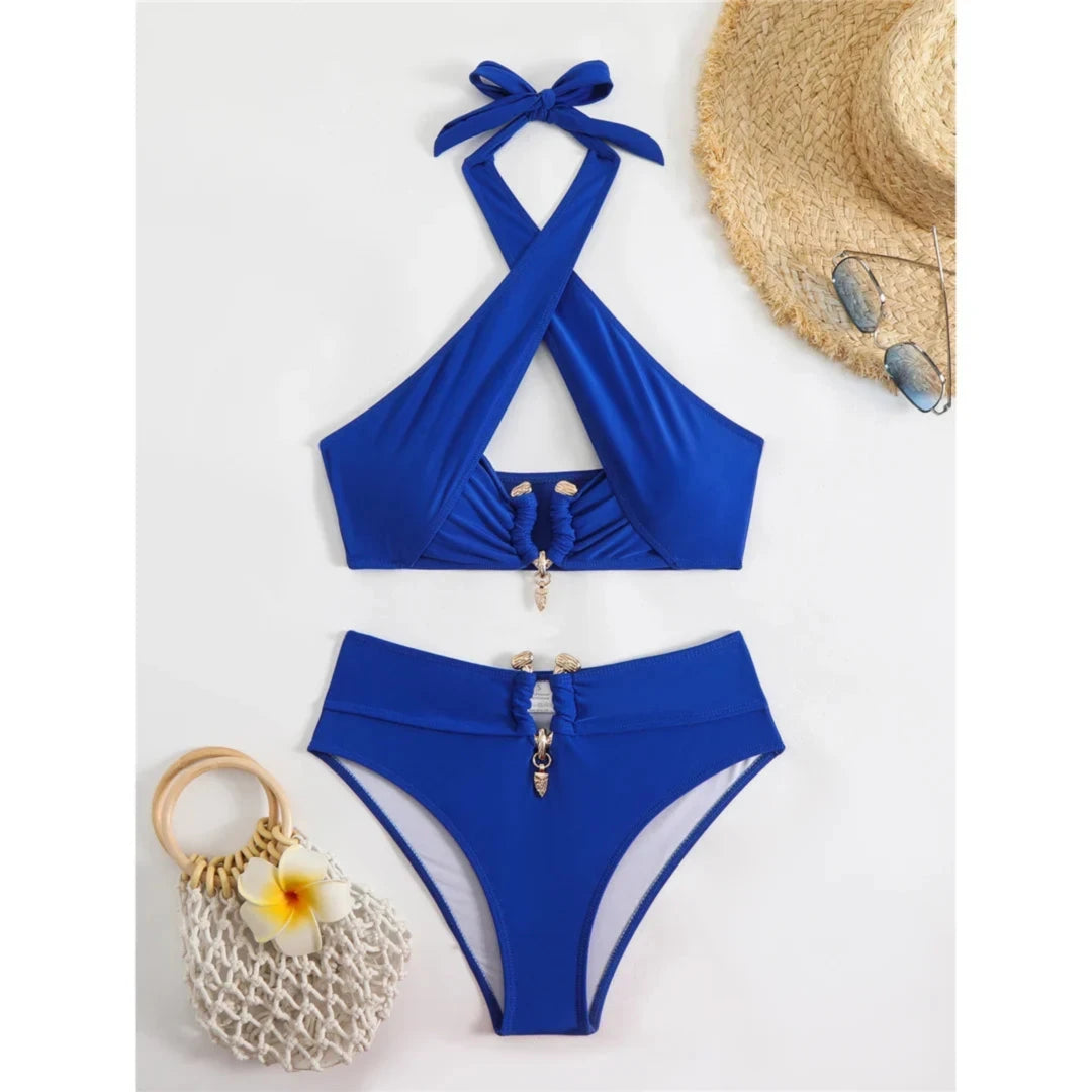 Bikini taille haute tour de cou à découpes bleu posé à plat sur fond blanc, chapeau de paille et lunettes à côté