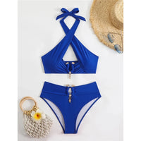 Bikini taille haute tour de cou à découpes bleu posé à plat sur fond blanc, chapeau de paille et lunettes à côté