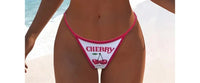 Gros plan sur le bas du maillot trois pièces crop top cerises blanc bordé rose fuchsia