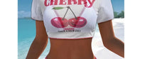 Gros plan sur le haut du maillot trois pièces crop top cerises blanc bordé rose fuchsia