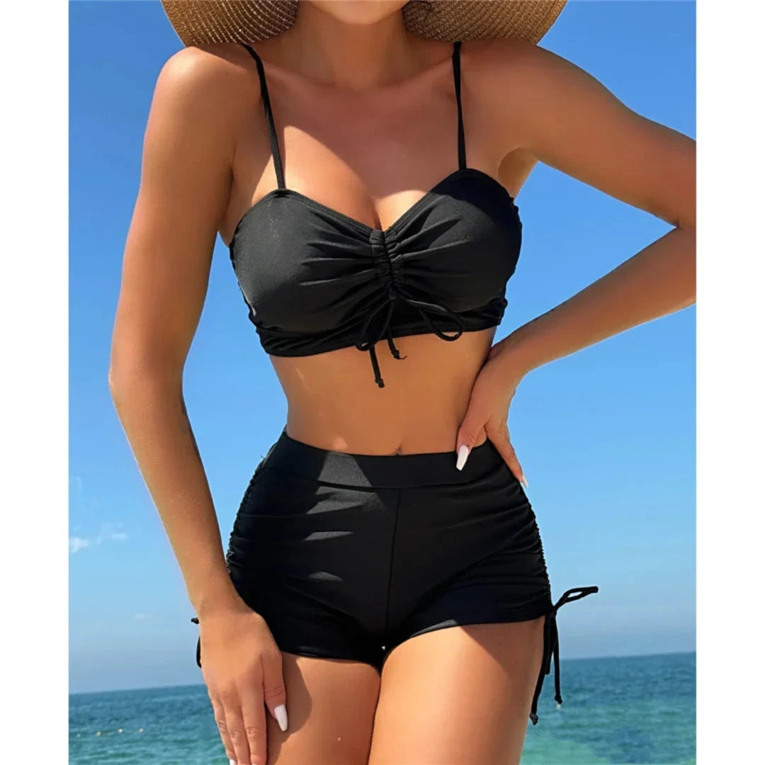 Bikini taille haute short froissé noir porté de face par une femme au chapeau de paille, bretelles fines et haut froncé