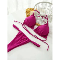 Bikini triangle froncé magenta posé à plat sur un fond blanc, près d'un panier en fil de fer