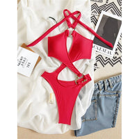 Maillot une pièce col halter rouge posé à plat sur un tissu blanc, bretelle croisée au cou et short en jean en bas