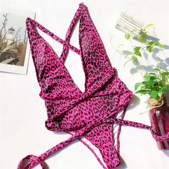 Maillot de bain une pièce triangle croisé imprimé léopard rose vif posé à plat, bretelles croisées et lacets latéraux