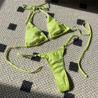 Bikini tour de cou pailleté vert fluo posé à plat sur un tapis à motifs, liens longs et bas à anneau