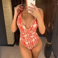 Maillot de bain une pièce triangle croisé imprimé serpent rouge porté de face en selfie, décolleté plongeant et taille cintrée