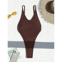 Maillot de bain une pièce marron café posé à plat sur fond blanc, bretelles fines, lunettes et chapeau à côté