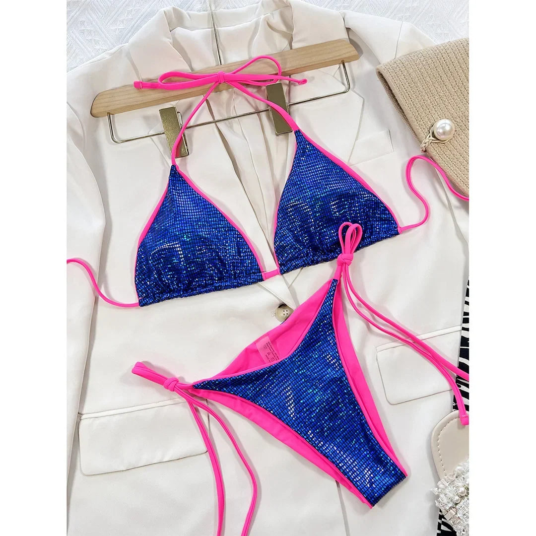Bikini brésilien tour de cou sans armatures bleu à reflets posé à plat sur une veste blanche, sous un cintre