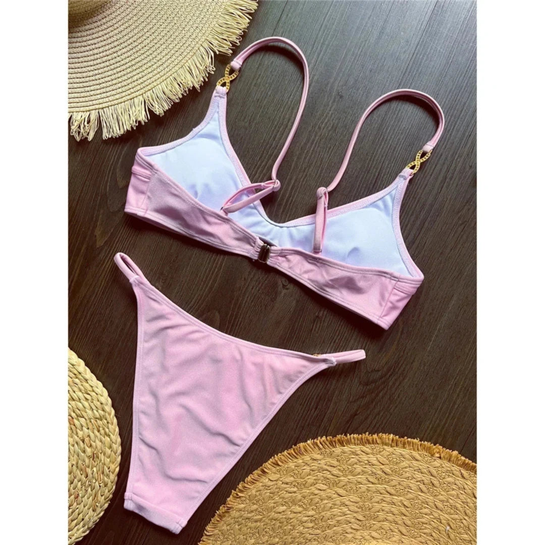 Bikini triangle rose vu de dos posé à plat sur une table en bois, doublure blanche visible et bretelles croisées