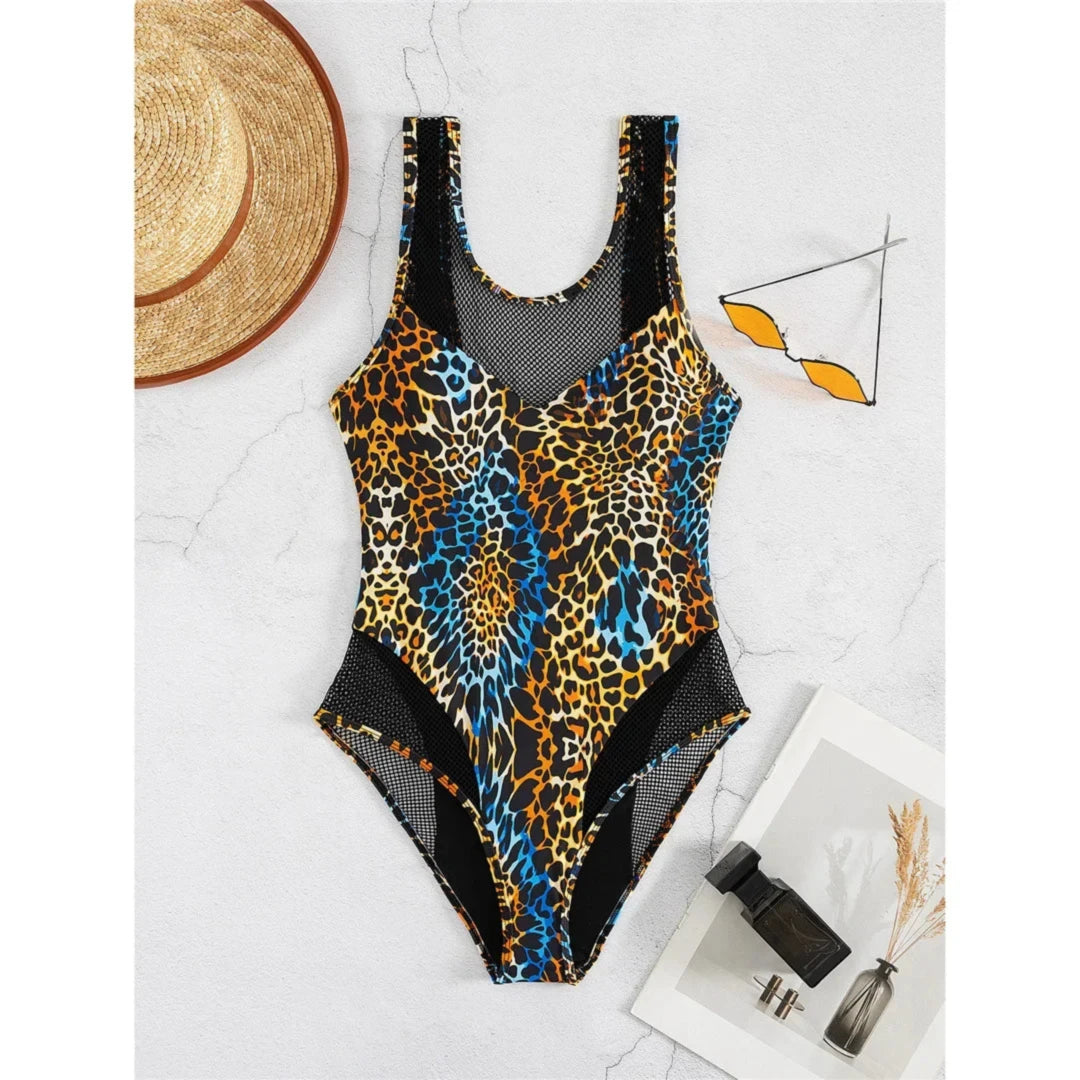 Maillot de bain une pièce résille dos nu échancré imprimé léopard posé à plat sur marbre blanc, lunettes et chapeau