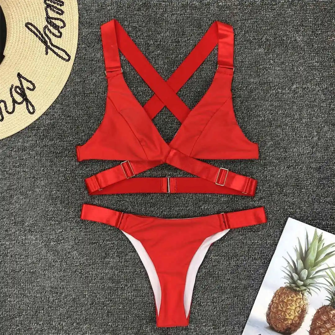 Bikini sans armatures croisé dans le dos rouge posé à plat sur un tapis gris, bretelles croisées et boucle centrale