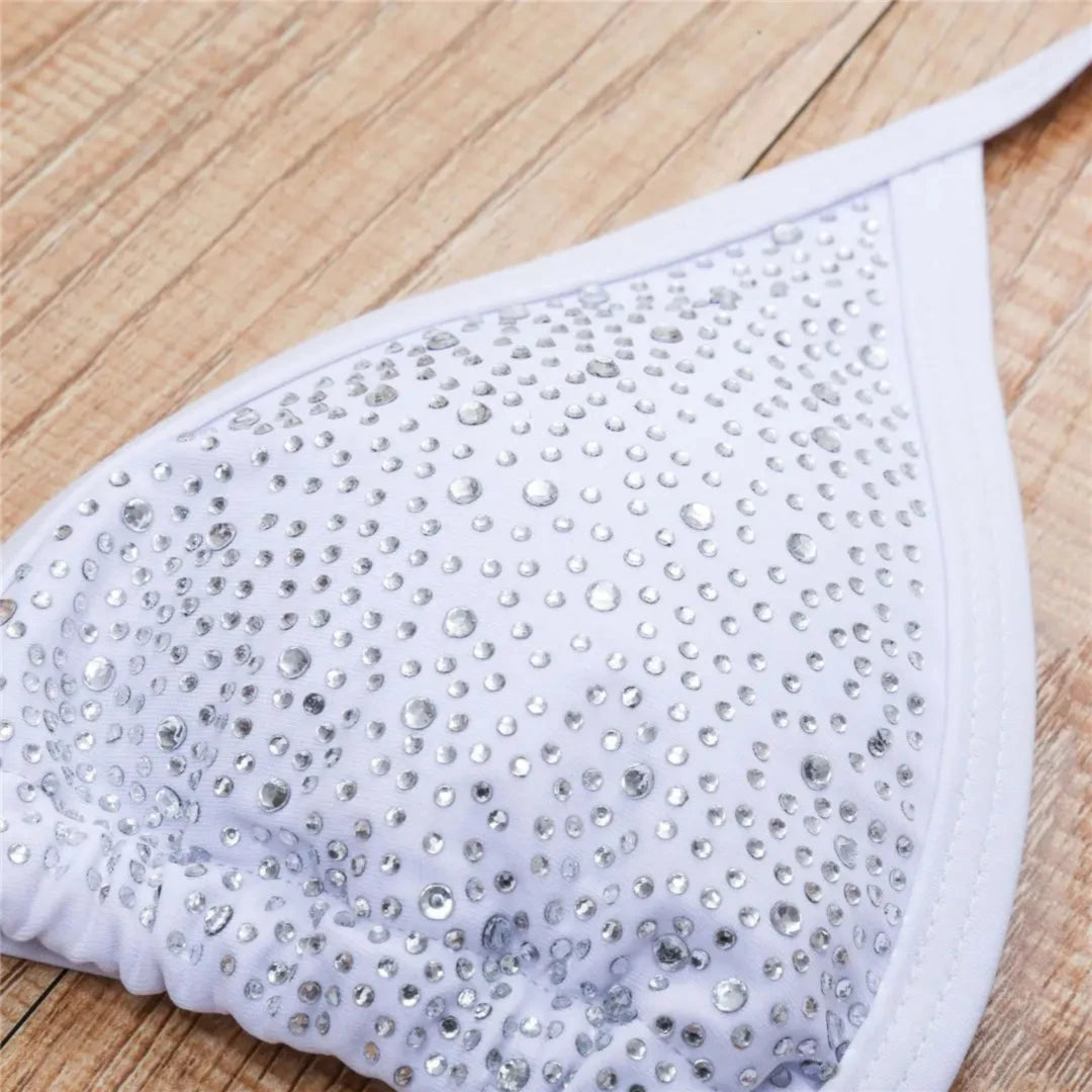 Gros plan sur le haut blanc couvert de strass argentés, petits strass répartis sur le triangle du bikini