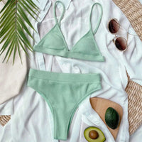 Bikini taille haute côtelé sans armatures vert menthe posé à plat sur une chemise blanche, avec un avocat