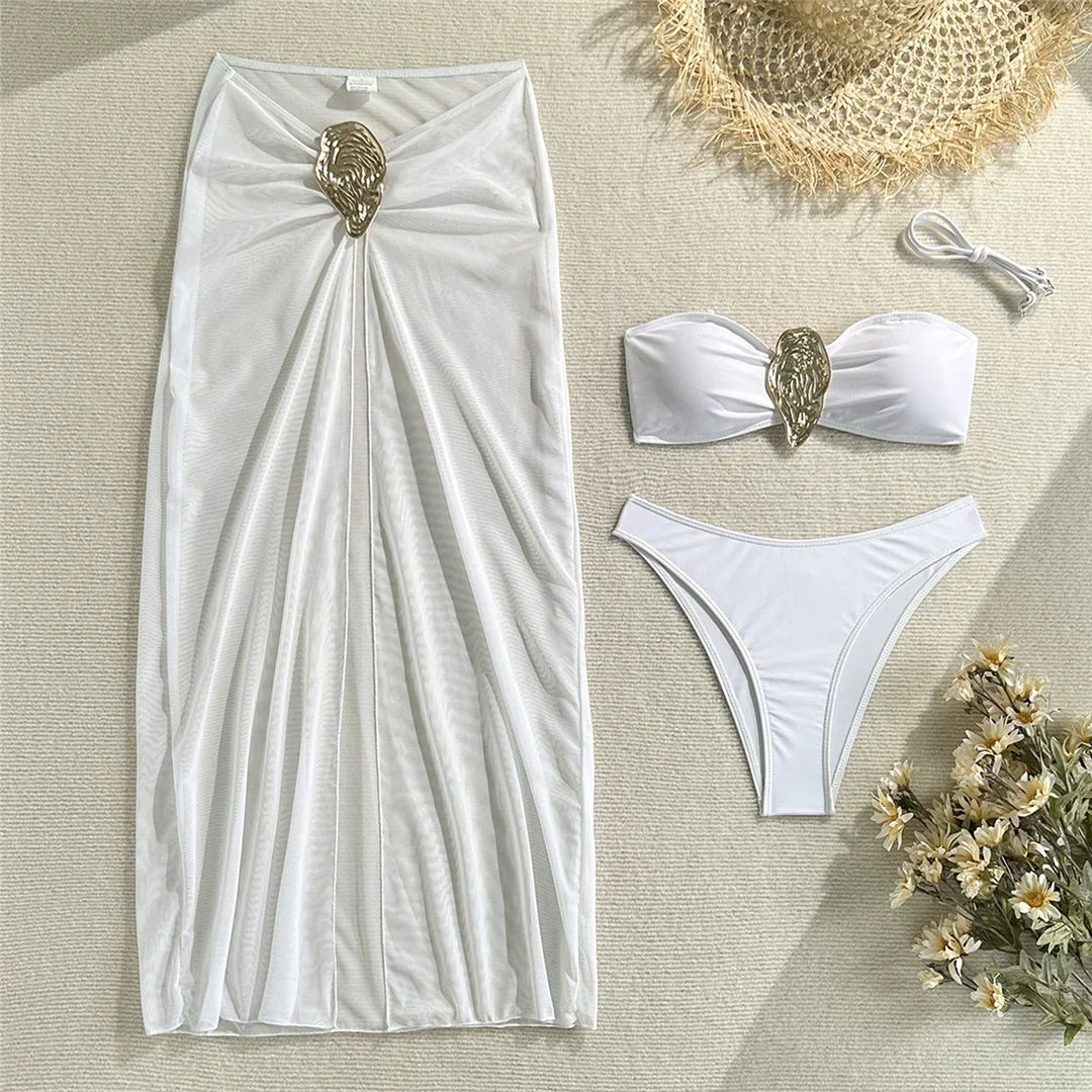 Maillot trois pièces blanc posé à plat avec la jupe longue et l'anneau doré, bas taille basse sur fond blanc