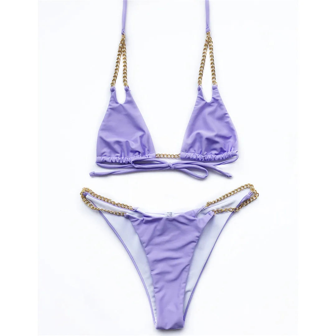 Bikini tour de cou à chaîne métallique violet posé à plat sur fond blanc, chaînes dorées sur les côtés de la culotte