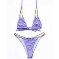Bikini tour de cou à chaîne métallique violet posé à plat sur fond blanc, chaînes dorées sur les côtés de la culotte