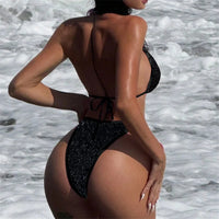 Bikini à paillettes col halter échancré taille basse noir vu de dos, attaches nouées dans le dos, au bord de l'eau
