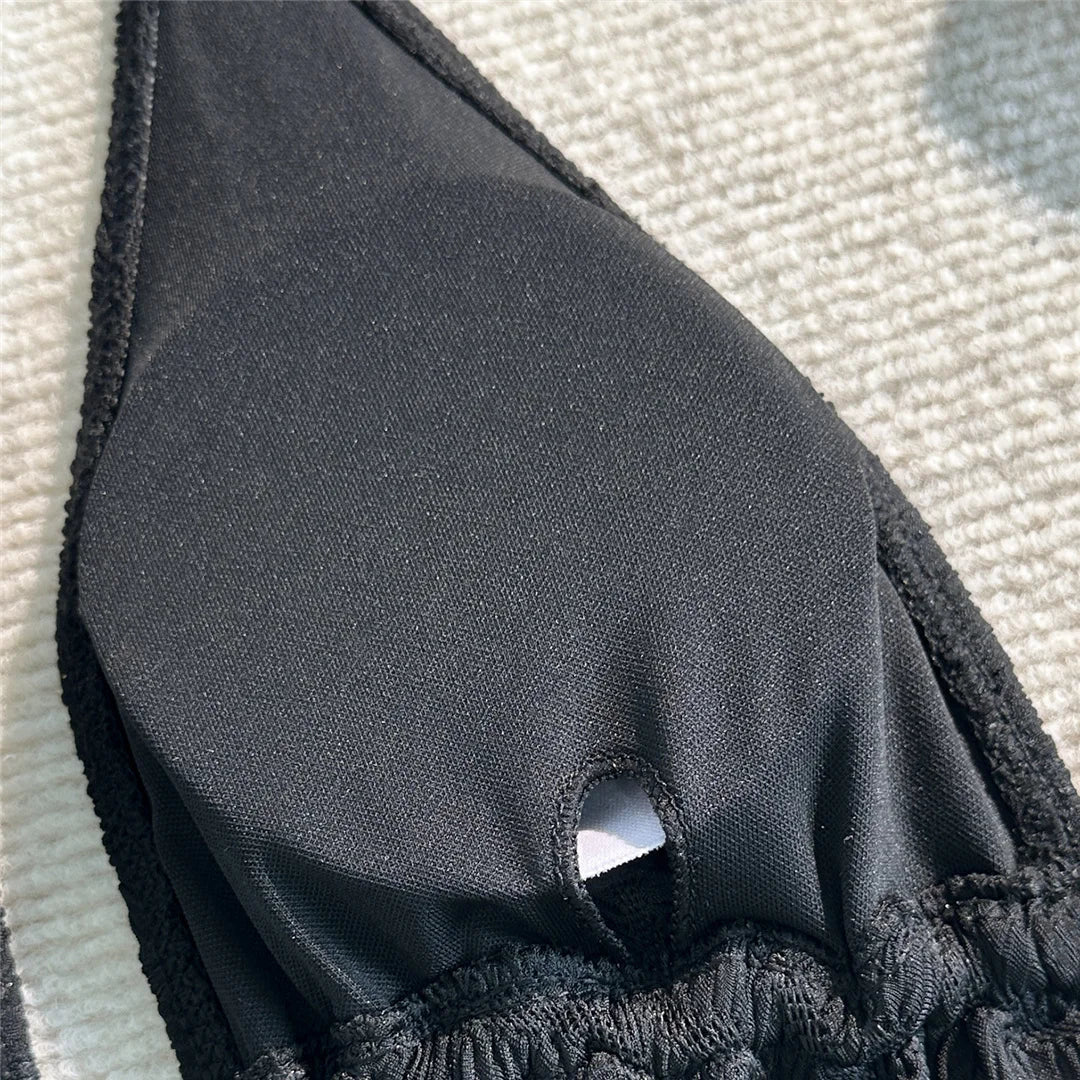 Gros plan sur la doublure intérieure du haut de maillot de bain trois pièces noir, anneau central et matière lisse