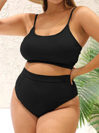 Bikini deux pièces grande taille côtelé taille haute noir porté de face, mains sur les hanches, plante verte à droite