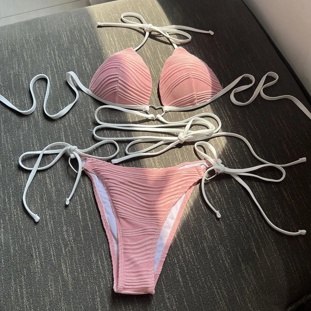 Bikini col halter croisé à effet froissé rose posé à plat, lacets blancs longs et slip à nouer sur les côtés