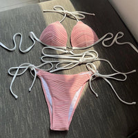 Bikini col halter croisé à effet froissé rose posé à plat, lacets blancs longs et slip à nouer sur les côtés