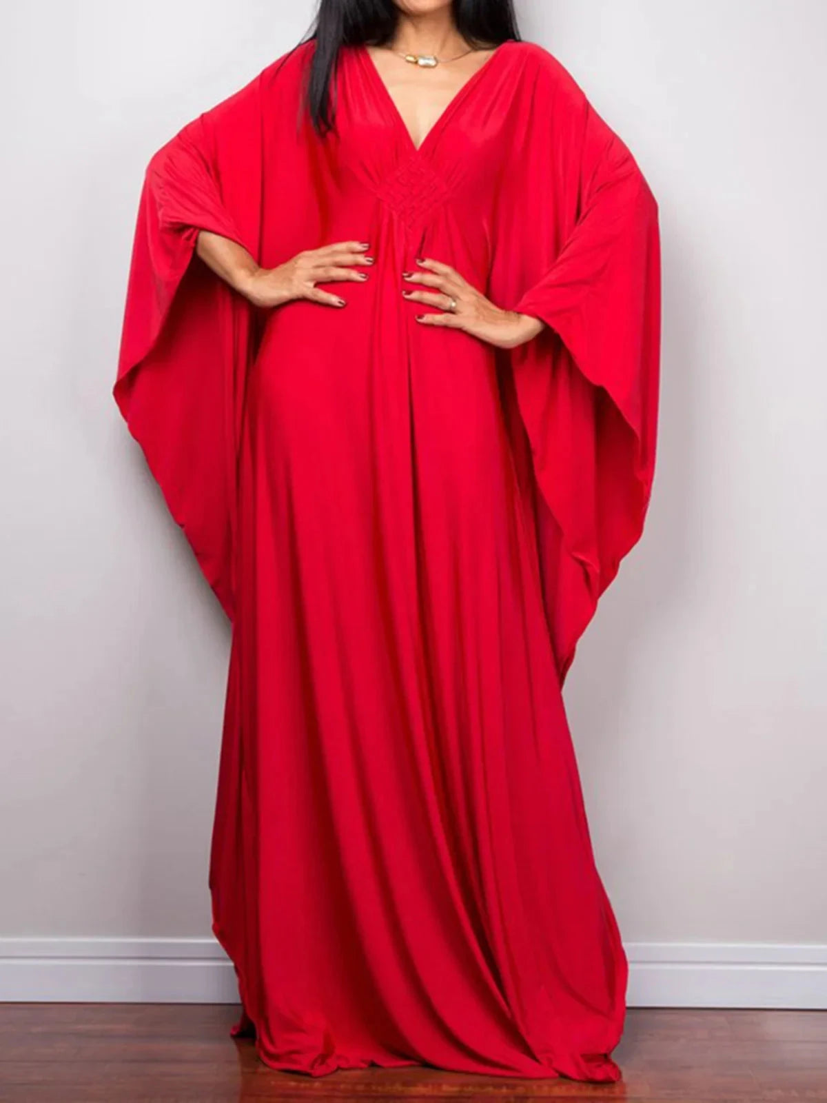 Robe de plage longue kaftan manches chauve-souris rouge portée de face en plan large, mains aux hanches et drapé fluide