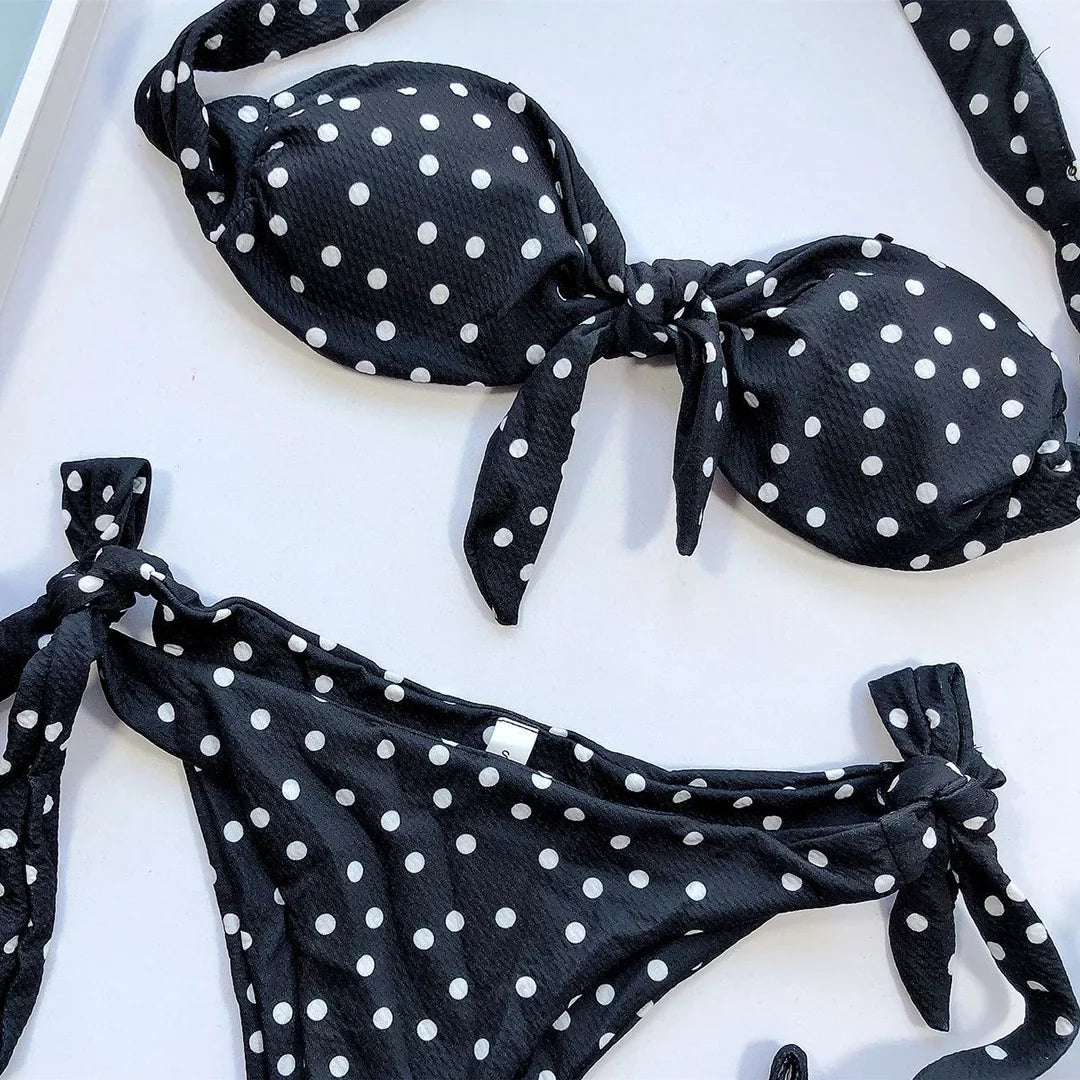 Gros plan sur le haut bandeau noir à pois noué devant, bas à nœuds sur les hanches, porté par une femme
