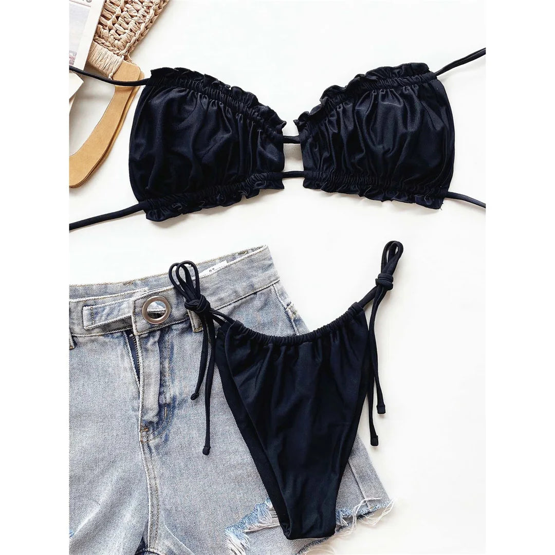 Bikini à volants froncé col halter bas à nouer noir à plat sur un short en jean, sandale en paille à gauche