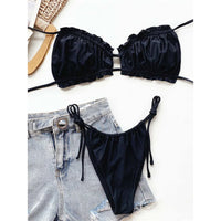 Bikini à volants froncé col halter bas à nouer noir à plat sur un short en jean, sandale en paille à gauche