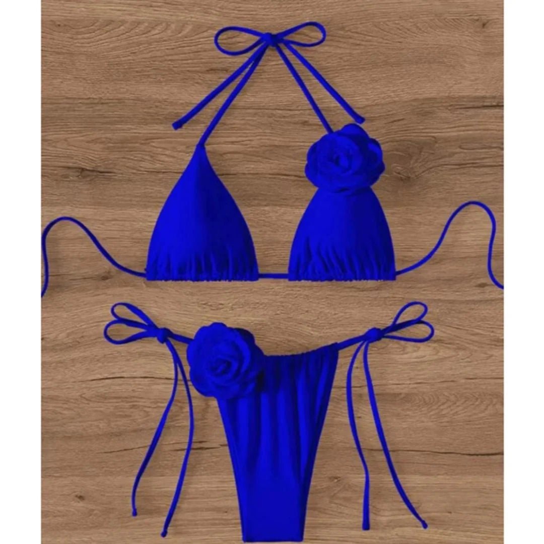 Bikini tour de cou à fleurs 3D et lanières bleu roi posé à plat sur bois, fleur en relief sur le haut et sur le bas