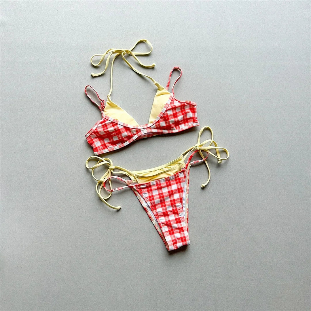Bikini à carreaux rouge et blanc posé à plat sur fond gris, liens jaune pâle à nouer et doublure jaune sur le haut
