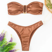 Bikini bandeau sans armatures taille basse marron posé à plat sur fond blanc, lavande et plante à côté, vue de dessus