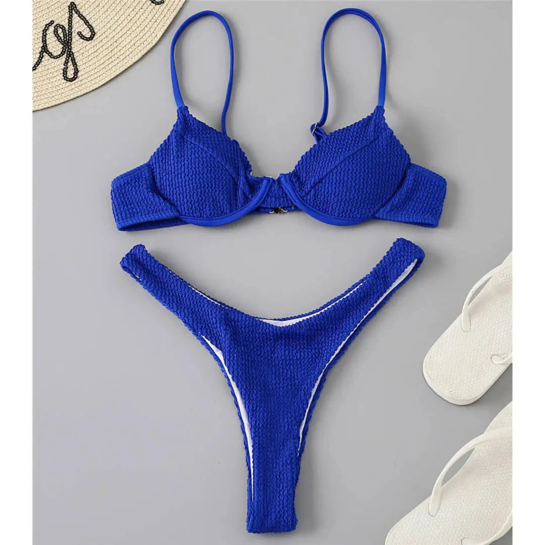 Bikini triangle à armatures côtelé échancré bleu roi posé à plat sur fond gris, tongs blanches à côté