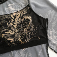 Gros plan sur le buste du body noir en mesh à grandes fleurs dessinées beiges, bande noire et tissu transparent