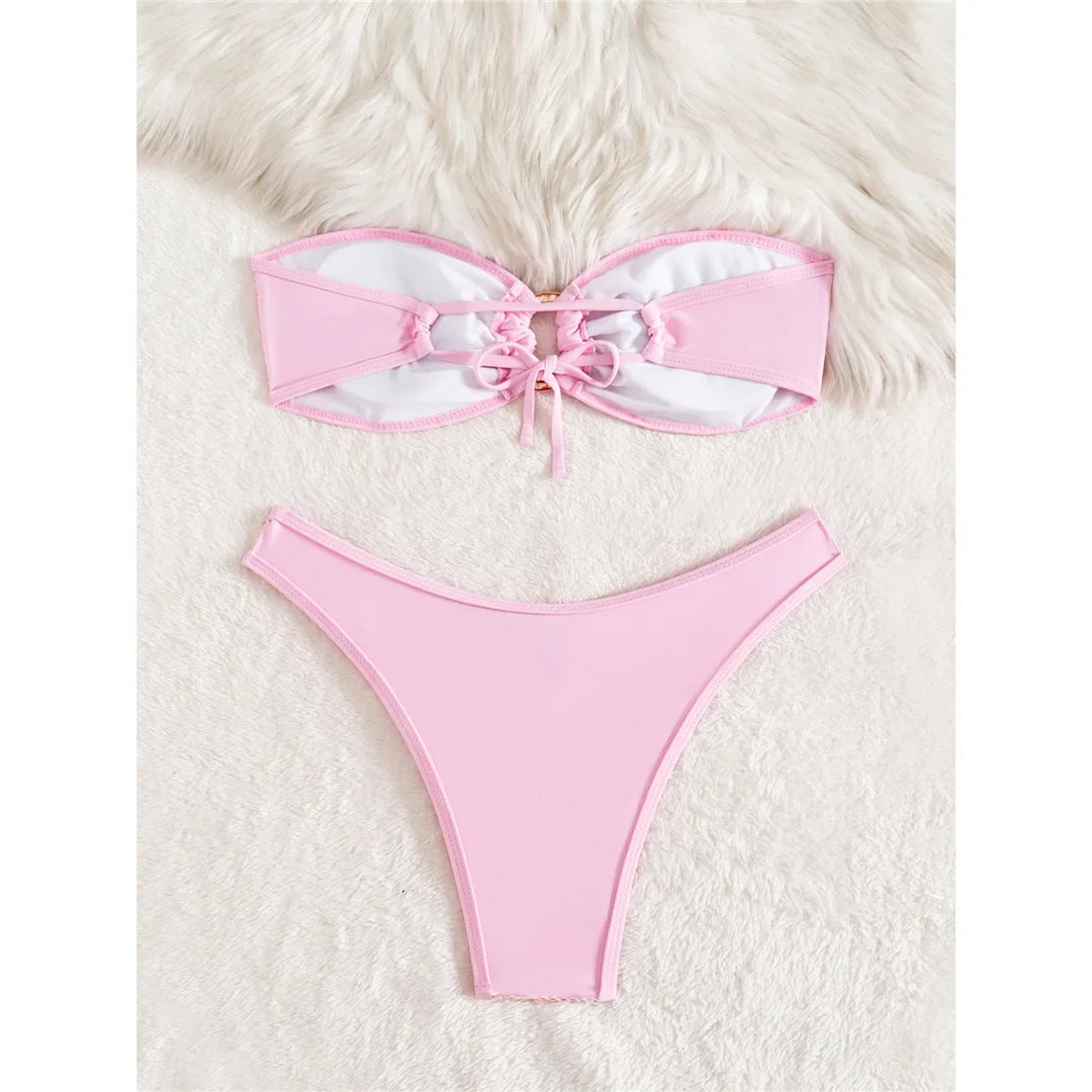Bikini bandeau rose taille basse version unie posée à plat, haut noué par un lacet au centre et slip lisse