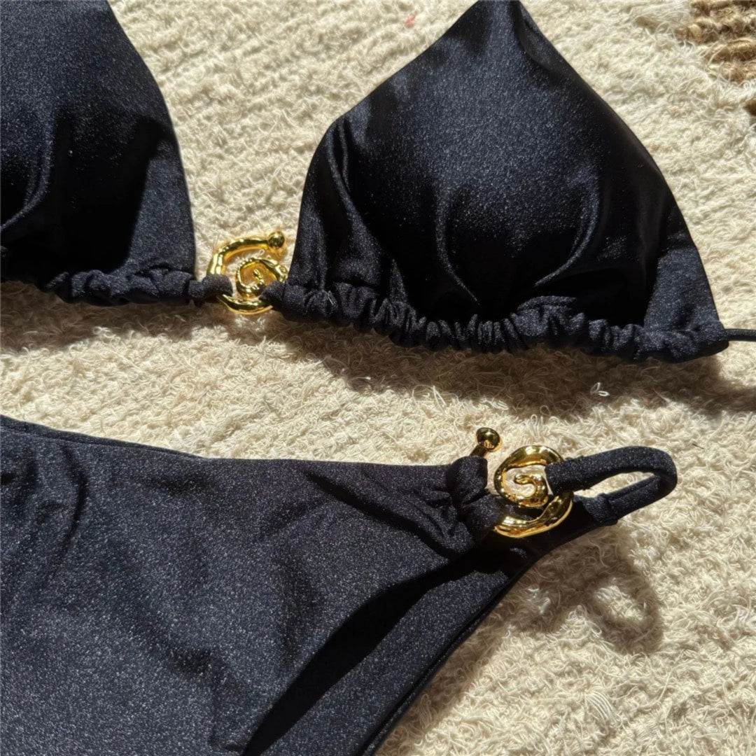 Gros plan sur l'anneau doré du bikini tour de cou à anneau métallique noir, bonnet froncé de part et d'autre