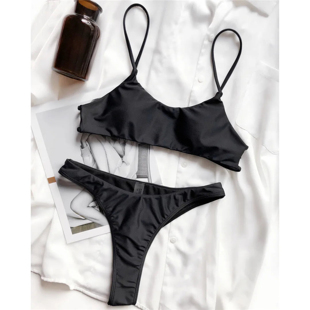 Bikini string brassière noir posé à plat sur une chemise blanche, à côté d'une bouteille brune et d'un magazine